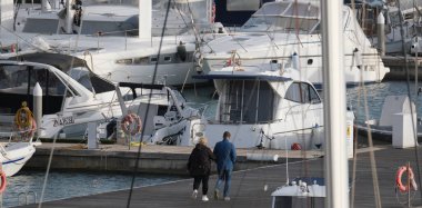 İtalya, Sicilya, Akdeniz, Marina di Ragusa (Ragusa Eyaleti); 10 Ocak 2025, limandaki insanlar, motorlu tekneler ve lüks yatlar - EDITORIAL