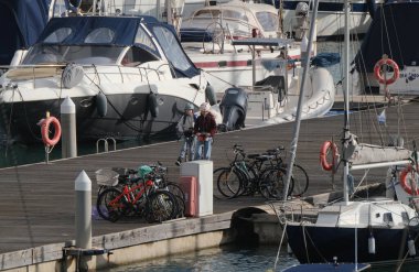 İtalya, Sicilya, Akdeniz, Marina di Ragusa (Ragusa Eyaleti); 12 Ocak 2025, limandaki bisiklet ve lüks yatlarda çocuklar - EDITORIAL