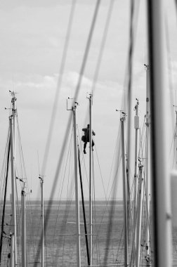 İtalya, Sicilya, Akdeniz, Marina di Ragusa (Ragusa Eyaleti), limanda yelkenli gemi direğinde çalışan adam.