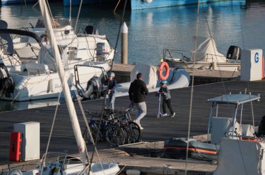 İtalya, Sicilya, Akdeniz, Marina di Ragusa (Ragusa ili); 18 Ocak 2025, limandaki bisiklet ve lüks yatlarda yaşayan insanlar - EDITORIAL