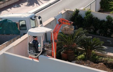 İtalya, Sicilya; Marina di Ragusa (Ragusa Eyaleti); 20 Ocak 2025, özel bir kazançta buldozer üzerinde çalışan adam - EDITORIAL