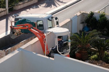 İtalya, Sicilya; Marina di Ragusa (Ragusa Eyaleti); 20 Ocak 2025, özel bir kazançta buldozer üzerinde çalışan adam - EDITORIAL