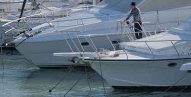 İtalya, Sicilya, Akdeniz, Marina di Ragusa (Ragusa Eyaleti); 4 Şubat 2025, limanda lüks bir yatta bir adam - EDITORIAL