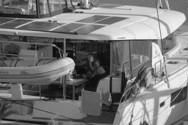 İtalya, Sicilya, Akdeniz, Marina di Ragusa (Ragusa Eyaleti); 4 Şubat 2025, limanda bir katamaran yelkenli teknesinde çift