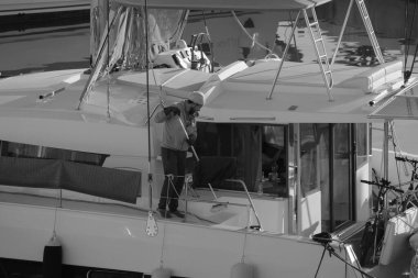 İtalya, Sicilya, Akdeniz, Marina di Ragusa (Ragusa Eyaleti); 4 Şubat 2025, limandaki bir katamaran yelkenli teknesinde adam - EDITORIAL