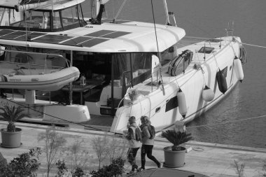 İtalya, Sicilya, Akdeniz, Marina di Ragusa (Ragusa Eyaleti); 4 Mart 2025, limanda insanlar ve bir katamaran yelkenli teknesi - EDITORIAL