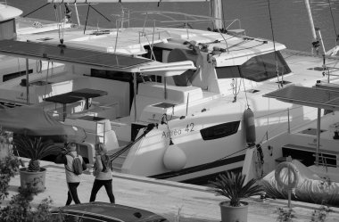 İtalya, Sicilya, Akdeniz, Marina di Ragusa (Ragusa Eyaleti); 4 Mart 2025, limanda insanlar ve katamaran yelkenli tekneleri - EDITORIAL