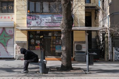Bulgaristan, Sofya; 9 Mart 2025, kentin orta sokağındaki bir bankta oturan Bulgar adam - EDITORIAL