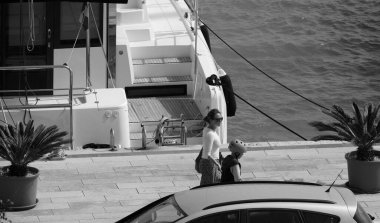 İtalya, Sicilya, Akdeniz, Marina di Ragusa (Ragusa Eyaleti); 15 Nisan 2025, limanda insanlar ve bir katamaran yelkenli teknesi - EDITORIAL