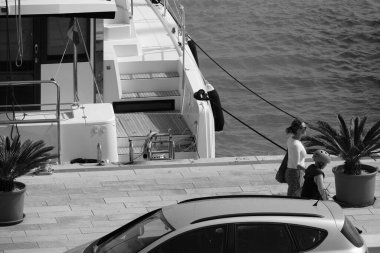 İtalya, Sicilya, Akdeniz, Marina di Ragusa (Ragusa Eyaleti); 15 Nisan 2025, limanda insanlar ve bir katamaran yelkenli teknesi - EDITORIAL