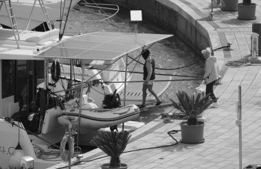 İtalya, Sicilya, Akdeniz, Marina di Ragusa (Ragusa Eyaleti); 16 Nisan 2025, limandaki katamaran yelkenli teknesinde insanlar - EDITORIAL