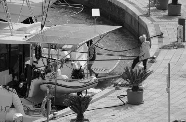 İtalya, Sicilya, Akdeniz, Marina di Ragusa (Ragusa Eyaleti); 16 Nisan 2025, limandaki katamaran yelkenli teknesinde insanlar - EDITORIAL