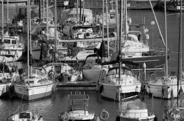 İtalya, Sicilya, Akdeniz, Marina di Ragusa (Ragusa Eyaleti); 30 Nisan 2025, limandaki bir yelkenli ve lüks yatlarda yaşayan insanlar - EDITORIAL