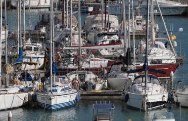 İtalya, Sicilya, Akdeniz, Marina di Ragusa (Ragusa Eyaleti); 30 Nisan 2025, limandaki bir yelkenli ve lüks yatlarda yaşayan insanlar - EDITORIAL