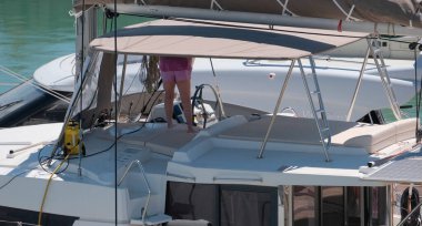 İtalya, Sicilya, Akdeniz, Marina di Ragusa (Ragusa Eyaleti); 1 Mayıs 2025, limanda katamaran yelkenlisini temizleyen kadın - EDITORIAL
