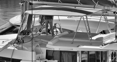 İtalya, Sicilya, Akdeniz, Marina di Ragusa (Ragusa Eyaleti); 1 Mayıs 2025, limanda katamaran yelkenlisini temizleyen kadın - EDITORIAL