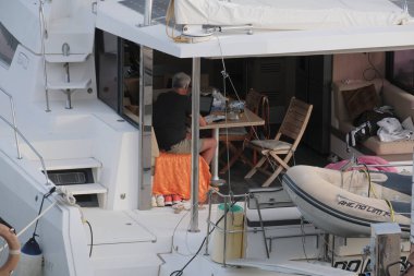 İtalya, Sicilya, Akdeniz, Marina di Ragusa (Ragusa Eyaleti); 5 Mayıs 2025, limandaki bir katamaran yelkenli teknesinde adam - EDITORIAL