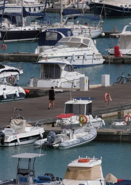 İtalya, Sicilya, Akdeniz, Marina di Ragusa (Ragusa Eyaleti); 6 Mayıs 2025, limanda kadın, motorlu tekne ve lüks yatlar - EDITORIAL