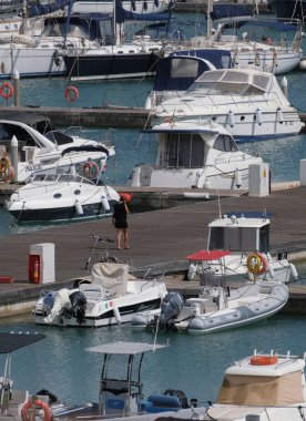 İtalya, Sicilya, Akdeniz, Marina di Ragusa (Ragusa Eyaleti); 6 Mayıs 2025, limanda kadın, motorlu tekne ve lüks yatlar - EDITORIAL