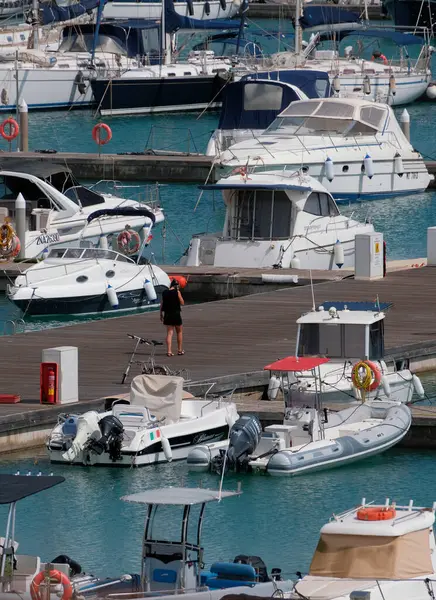 İtalya, Sicilya, Akdeniz, Marina di Ragusa (Ragusa Eyaleti); 6 Mayıs 2025, limanda kadın, motorlu tekne ve lüks yatlar - EDITORIAL