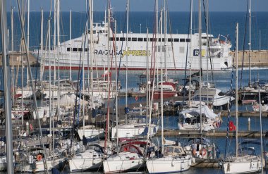 İtalya, Sicilya, Akdeniz, Marina di Ragusa (Ragusa ili); 13 Mayıs 2025, Sicilya 'yı Malta adasına bağlayan feribot ve limandaki lüks yatlar - EDITORIAL