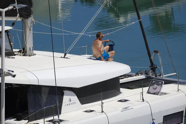 İtalya, Sicilya, Akdeniz, Marina di Ragusa (Ragusa Eyaleti); 3 Haziran 2025, limandaki bir katamaran yelkenli teknesinde adam - EDITORIAL