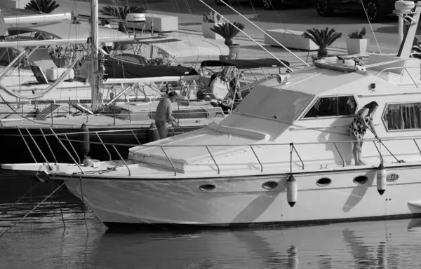 İtalya, Sicilya, Akdeniz, Marina di Ragusa (Ragusa Eyaleti); 7 Haziran 2025, limanda lüks bir yatı temizleyen çift - EDITORIAL