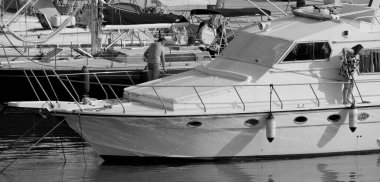 İtalya, Sicilya, Akdeniz, Marina di Ragusa (Ragusa Eyaleti); 7 Haziran 2025, limanda lüks bir yatı temizleyen çift - EDITORIAL