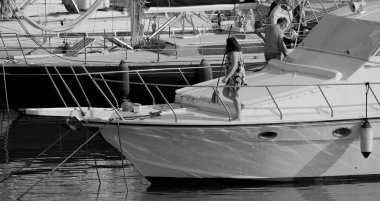 İtalya, Sicilya, Akdeniz, Marina di Ragusa (Ragusa Eyaleti); limanda lüks bir yatı temizleyen çift 