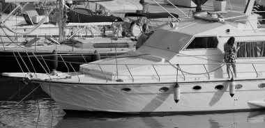 İtalya, Sicilya, Akdeniz, Marina di Ragusa (Ragusa Eyaleti); limanda lüks bir yatı temizleyen çift 