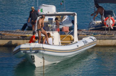 İtalya, Sicilya, Akdeniz, Marina di Ragusa (Ragusa ili); 15 Haziran 2025, limandaki büyük bir kauçuk teknede insanlar - EDITORIAL