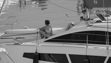 İtalya, Sicilya, Akdeniz, Marina di Ragusa (Ragusa ili); 17 Haziran 2025, limandaki bir katamaran yelkenli teknesinde insanlar - EDITORIAL