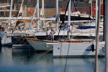 İtalya, Sicilya, Akdeniz, Marina di Ragusa (Ragusa ili); 19 Haziran 2025, limanda bir yelkenli ve lüks yatlarda erkekler - EDITORIAL