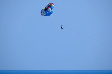 İtalya; Sicilya, Marina di Ragusa (Ragusa Eyaleti); bir motorlu tekne tarafından çekilen paraglider üzerindeki adam 