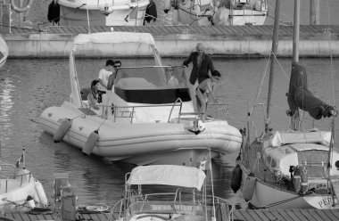 İtalya, Sicilya, Akdeniz, Marina di Ragusa (Ragusa ili); 21 Haziran 2025, limandaki kauçuk bir teknede insanlar - EDITORIAL