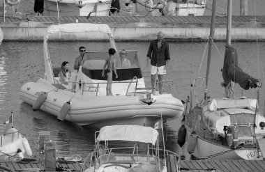 İtalya, Sicilya, Akdeniz, Marina di Ragusa (Ragusa ili); 21 Haziran 2025, limandaki kauçuk bir teknede insanlar - EDITORIAL