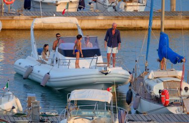 İtalya, Sicilya, Akdeniz, Marina di Ragusa (Ragusa ili); 21 Haziran 2025, limandaki kauçuk bir teknede insanlar - EDITORIAL