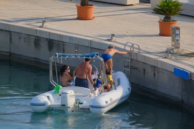 İtalya, Sicilya, Akdeniz, Marina di Ragusa (Ragusa ili); 22 Haziran 2025, limandaki kauçuk bir teknede insanlar - EDITORIAL