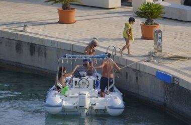 İtalya, Sicilya, Akdeniz, Marina di Ragusa (Ragusa ili); 22 Haziran 2025, limandaki kauçuk bir teknede insanlar - EDITORIAL