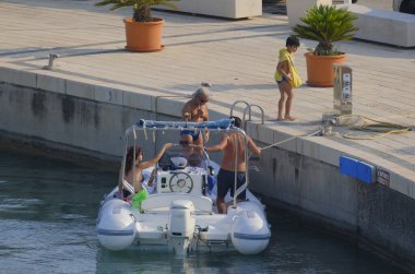 İtalya, Sicilya, Akdeniz, Marina di Ragusa (Ragusa ili); 22 Haziran 2025, limandaki kauçuk bir teknede insanlar - EDITORIAL