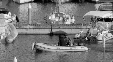 İtalya, Sicilya, Akdeniz, Marina di Ragusa (Ragusa ili); 24 Haziran 2025, limandaki kauçuk bir teknede adamlar - EDITORIAL