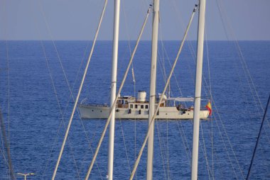 İtalya, Sicilya, Akdeniz, Marina di Ragusa (Ragusa Eyaleti); limanda yelken direkleri ve arka planda lüks bir yat