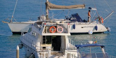 İtalya, Sicilya, Akdeniz, Marina di Ragusa (Ragusa Eyaleti); 27 Haziran 2025, limandaki bir yelkenli ve lüks yatlarda adam - EDITORIAL