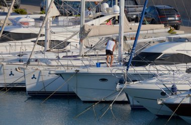 İtalya, Sicilya, Akdeniz, Marina di Ragusa (Ragusa Eyaleti); 9 Temmuz 2025; limanda lüks bir yatı temizleyen adam - EDITORIAL