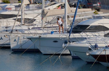 İtalya, Sicilya, Akdeniz, Marina di Ragusa (Ragusa Eyaleti); 9 Temmuz 2025; limanda lüks bir yatı temizleyen adam - EDITORIAL