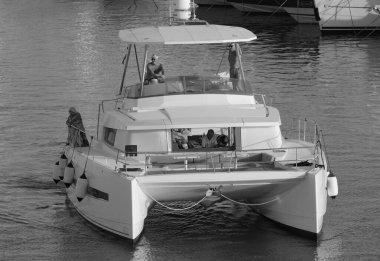 İtalya, Sicilya, Akdeniz, Marina di Ragusa (Ragusa Eyaleti); 13 Temmuz 2025, limandaki katamaran yelkenli teknesinde insanlar - EDITORIAL