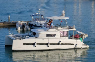 İtalya, Sicilya, Akdeniz, Marina di Ragusa (Ragusa Eyaleti); 13 Temmuz 2025, limandaki katamaran yelkenli teknesinde insanlar - EDITORIAL