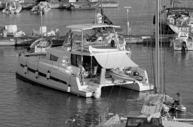 İtalya, Sicilya, Akdeniz, Marina di Ragusa (Ragusa Eyaleti); 13 Temmuz 2025, limandaki katamaran yelkenli teknesinde insanlar - EDITORIAL