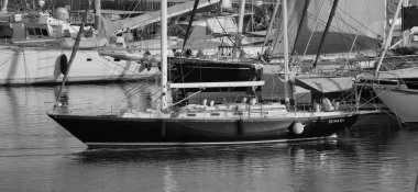 İtalya, Sicilya, Akdeniz, Marina di Ragusa (Ragusa Eyaleti); 16 Temmuz 2025, limanda bir yelkenli teknesi ve lüks yatlarda bir çift - EDITORIAL