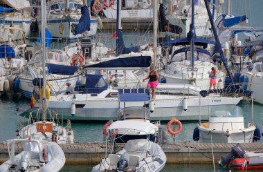 İtalya, Sicilya, Akdeniz, Marina di Ragusa (Ragusa ili); 18 Temmuz 2025, limandaki bir yelkenli teknesinde insanlar - EDITORIAL